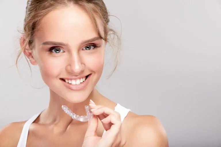 a woman holding invisalign clear aligners after considering aligners vs braces in Bakersfield and Tehachapi, CA