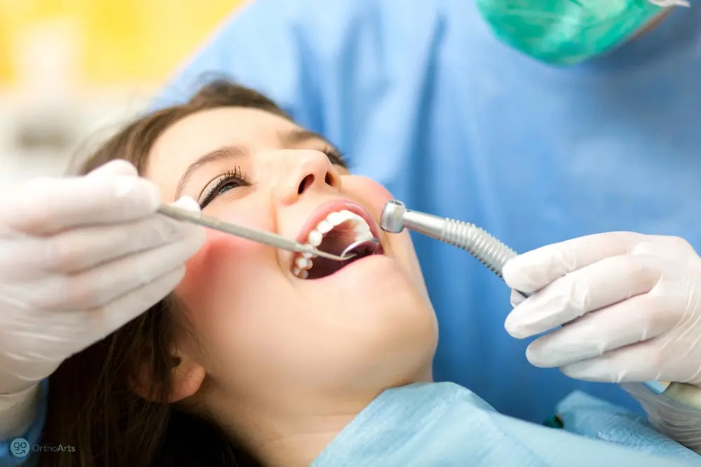 A patient undergoing a dental procedure with tools in her mouth, representing clinical treatments for how to fix overbite in Bakersfield and Tehachapi, CA.