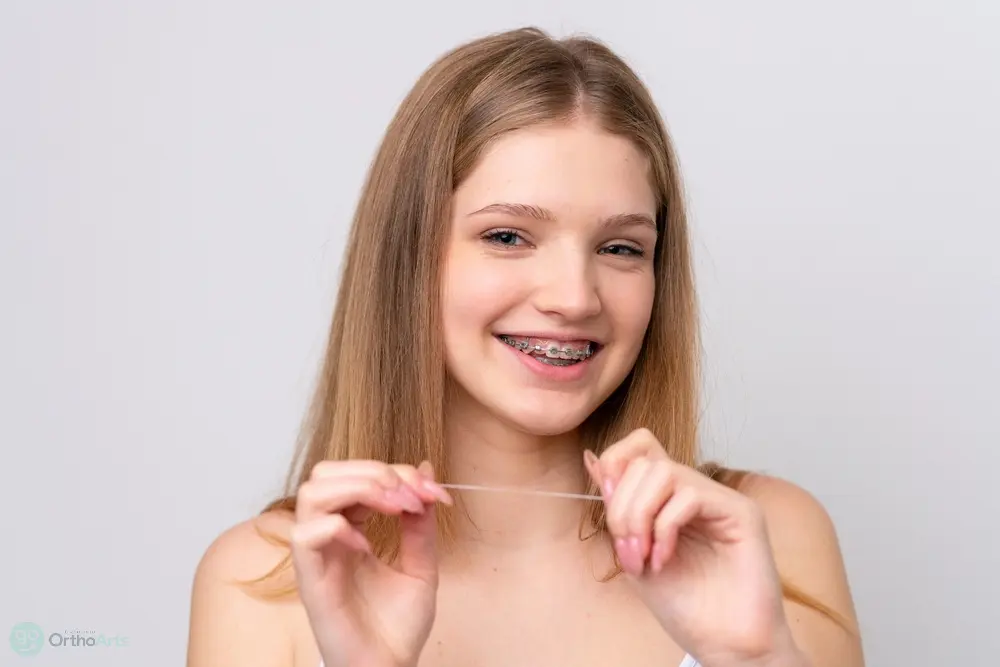 teenager russian girl with metal braces and floss isolated white background - How to Floss with Braces in Bakersfield and Tehachapi, CA.