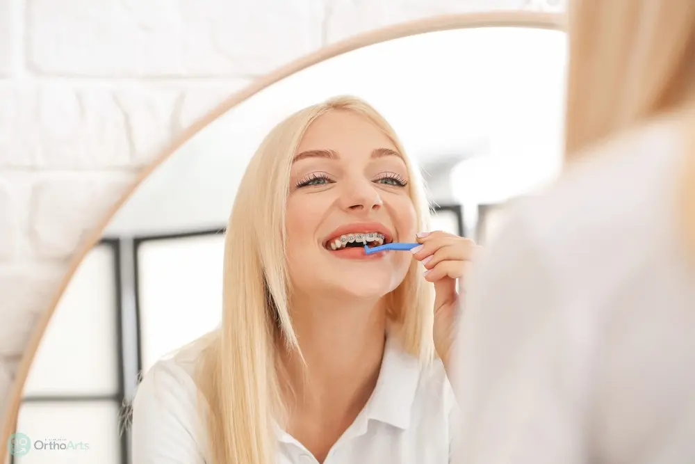 young woman metal braces toothbrush home - How to Floss with Braces in Bakersfield and Tehachapi, CA.