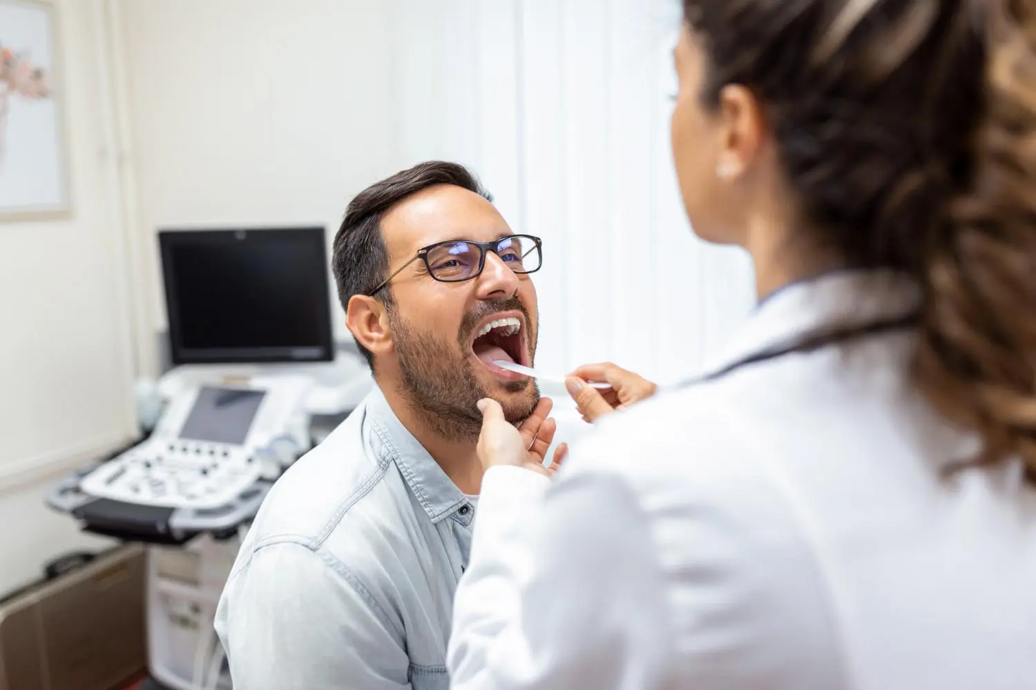 In an exam room, a doctor checks a man's throat for tongue thrust treatment at Gianquinto Orthodontic Arts in Bakersfield, Tehachapi or Mammoth Lakes, CA.