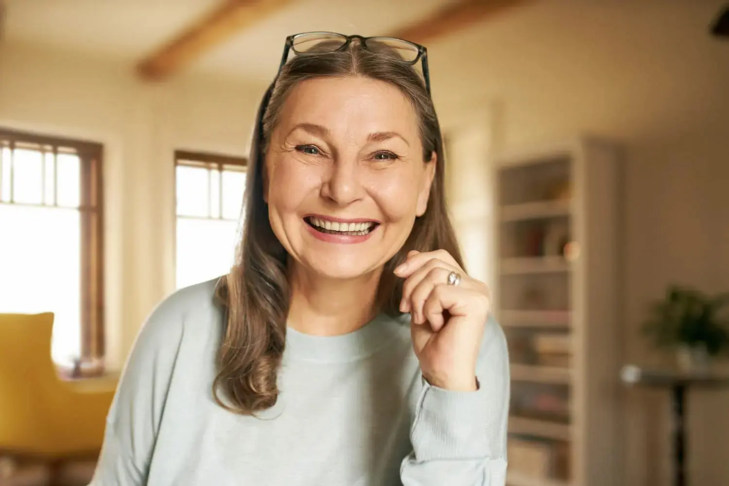 A middle-aged woman smiles indoors representing Best Dental Insurance for Adult Braces at Gianquinto Orthodontic Arts in Bakersfield, Tehachapi or Mammoth Lakes, CA