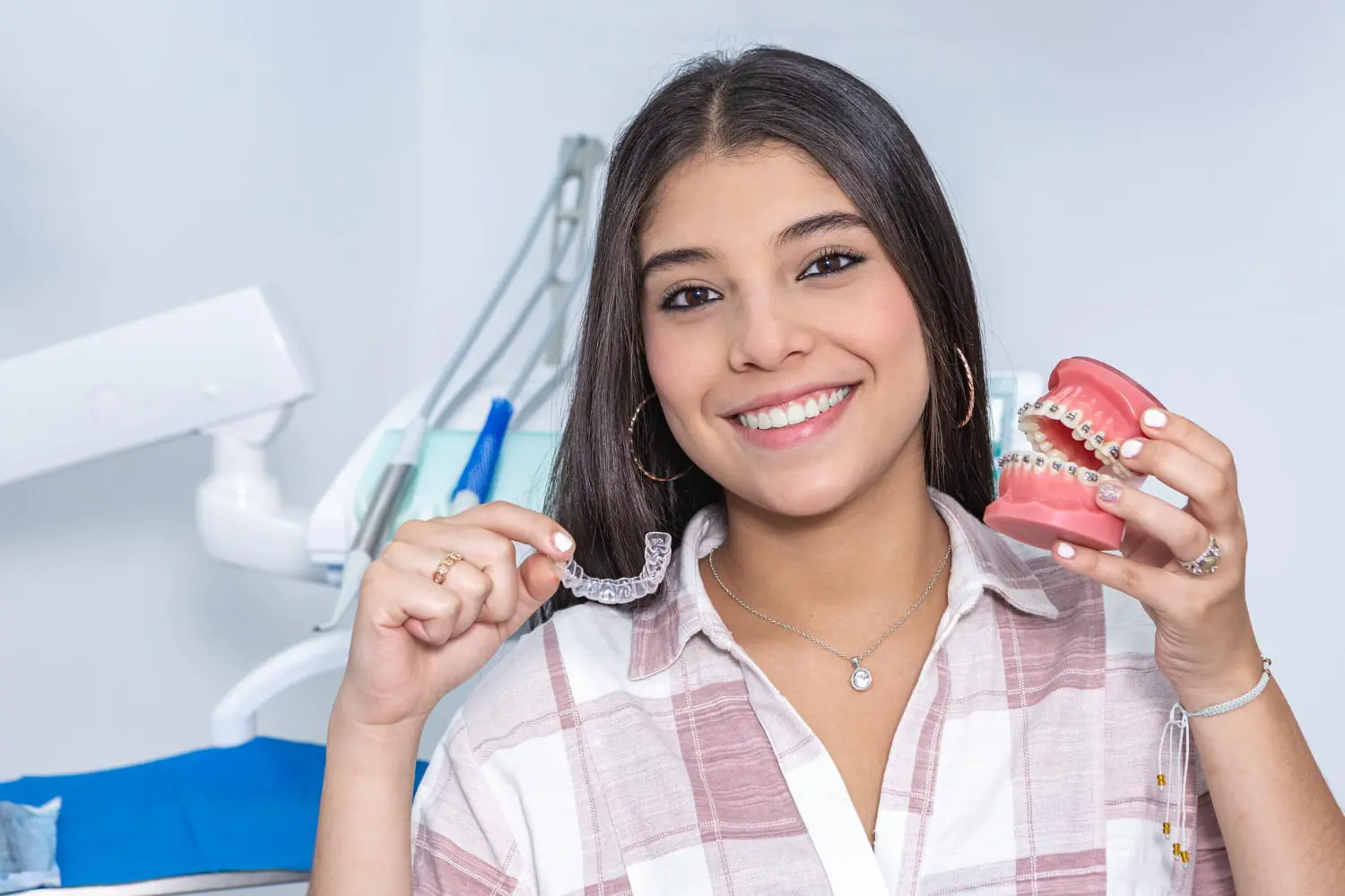 At Gianquinto Orthodontic Arts in Tehachapi, CA, a woman smiles holding braces and Invisalign.