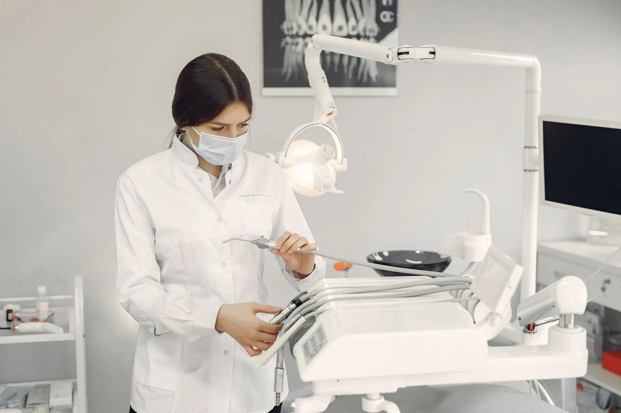 In Bakersfield, Tehachapi and Mammoth Lakes WA, a masked dentist at Gianquinto Orthodontic Arts prepares instruments in a modern office accepting orthodontic insurance.