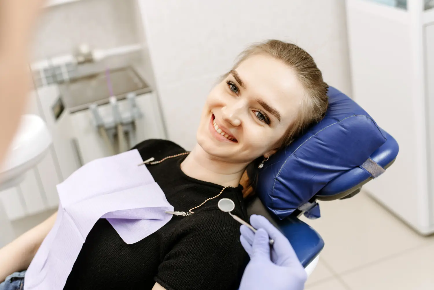 A woman smiles in a dental chair near orthodontic appliances, highlighting Gianquinto Orthodontic Arts in Bakersfield, CA.