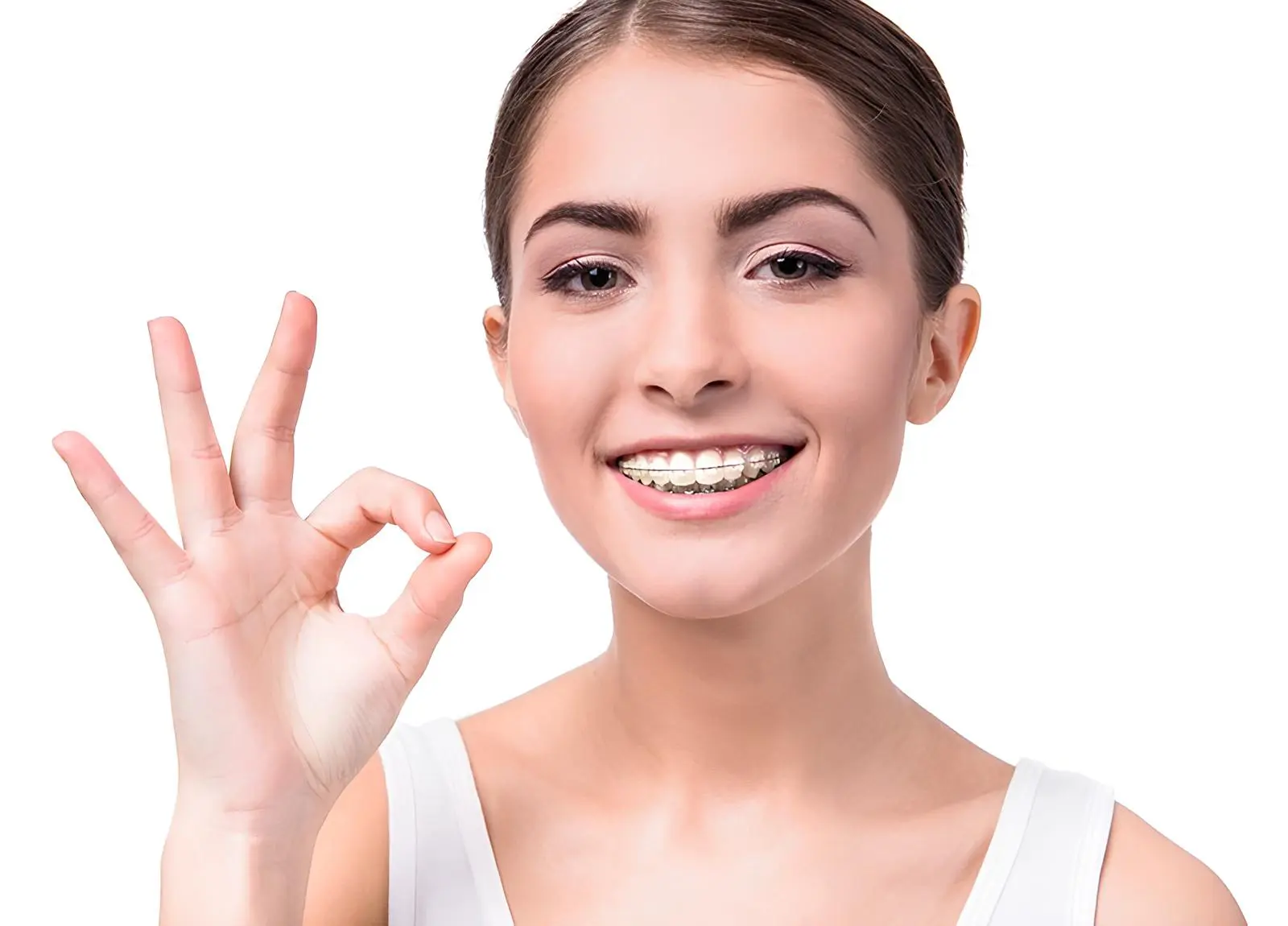 Smiling young woman with ceramic braces gives an "OK" gesture, representing Gianquinto Orthodontic Arts in Mammoth Lakes, CA.