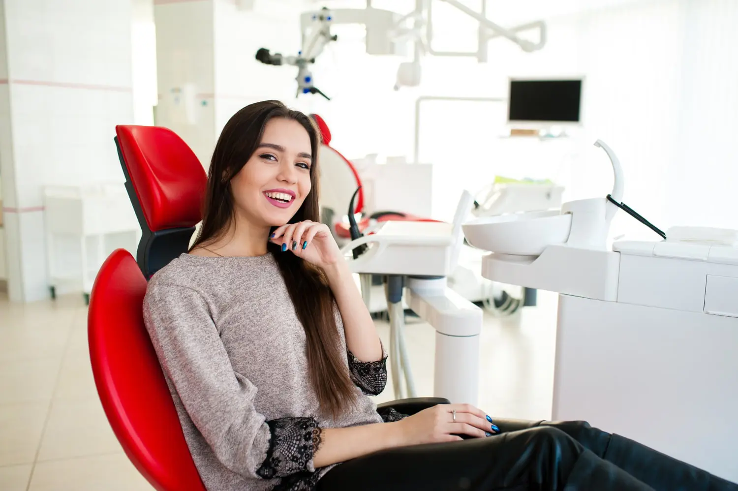 A woman smiles in a red dental chair at Gianquinto Orthodontic Arts in Bakersfield, Tehachapi or Mammoth Lakes, CA, ready for Airway Orthodontics.