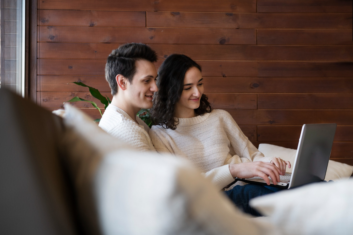 Two people sitting on a couch looking at a laptop and searching for affordable orthodontists for braces at Gianquinto Orthodontic Arts in Bakersfield, Tehachapi or Mammoth Lakes, CA