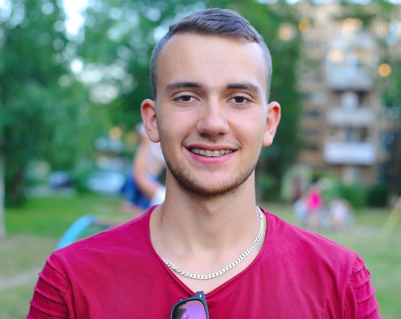 Smiling with clear braces from Gianquinto Orthodontic Arts in Bakersfield, CA, a young man stands outdoors.