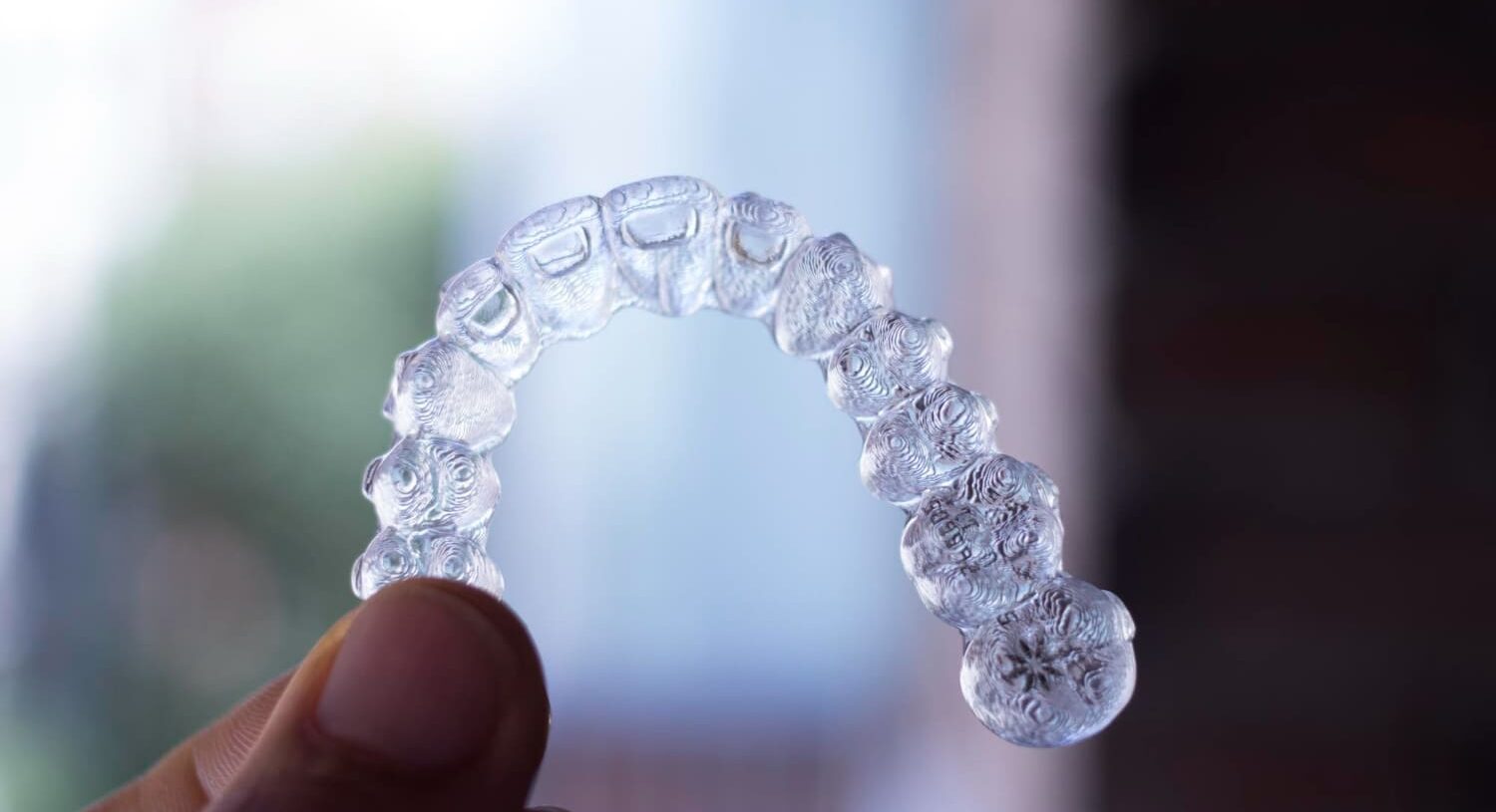A hand holds a Invisalign clear dental aligner from Gianquinto Orthodontic Arts in Tehachapi, CA