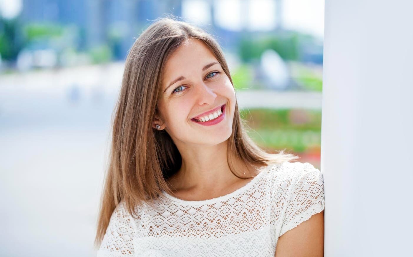 A young woman smiles outdoors, thinking about Invisalign be Covered by Insurance at Gianquinto Orthodontic Arts in Bakersfield, Tehachapi or Mammoth Lakes, CA